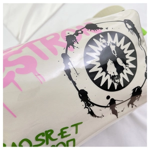 Detailed view of white canvas bag with pink graffiti letters and black sun logo print