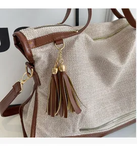 Detail of tweed Boston bag with brown leather trim and dual-tone tassel pendant hardware