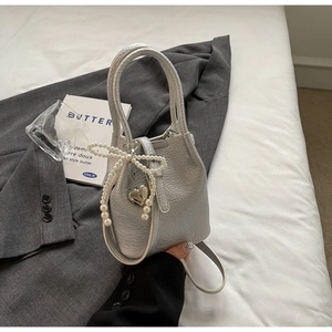 Détails du sac seau argenté texturé avec nœud en perles et pendentif cœur élégant