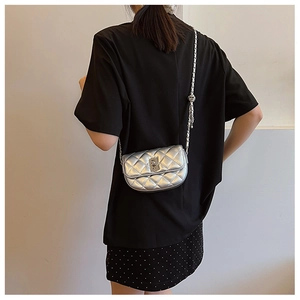 Detail of silver quilted crossbody bag with metal chain strap and turn-lock closure
