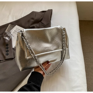 Close-up of silver chain strap on glossy wrinkled handbag with embossed logo detail