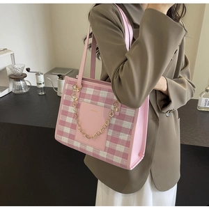 Detail of pink plaid tote bag featuring leather pocket and gold floral chain ornament
