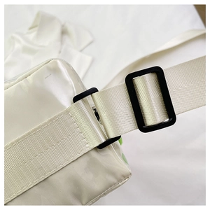 Detail of wide white woven strap with durable black plastic buckle on crossbody bag