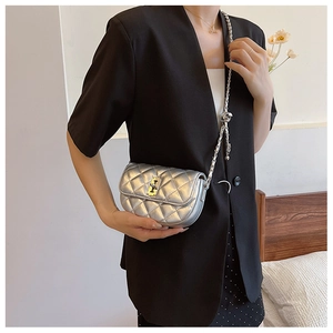 Silver quilted saddle bag with chain strap styled on model with black blazer and skirt