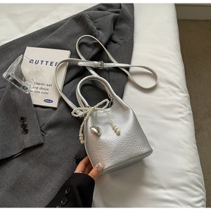 Détail du sac seau argenté avec nceud en perles et pendentif coeur en cuir