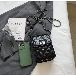 Detail of black quilted patent leather phone bag with silver chain and twist lock