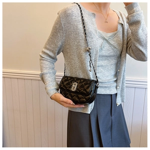 Detail of black quilted crossbody bag with silver chain strap and metal ball adjuster