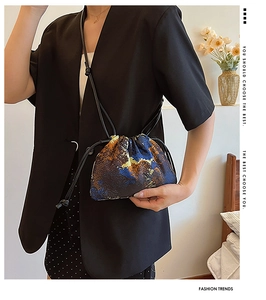 Close-up of abstract oil painting pattern on a canvas drawstring bucket bag worn by model