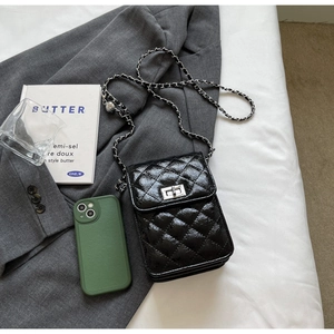 Close-up of black quilted leather crossbody bag with silver chain and twist lock