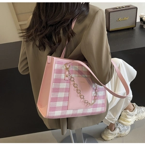 Detail of pink plaid tote bag featuring a leather pocket and gold floral chain