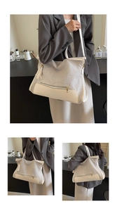 Detail of large beige and off-white tote bag with gold zipper and leather tassel
