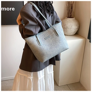 Close-up of light blue textured leather tote bag showing fine stitching and handle detail