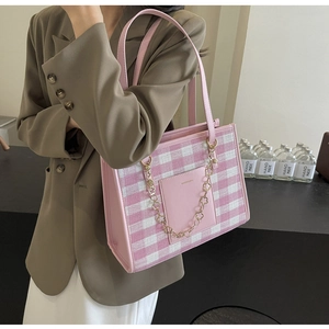Detail of pink plaid tote bag with golden chain strap on a model for daily commute