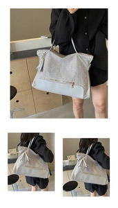 Detail of grey canvas tote bag with white leather trim, side view and metal tassel