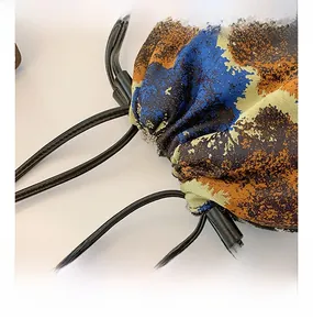 Detailed macro view of oil painting style fabric texture and dual drawstrings on bucket bag