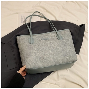 Detail of the gray-blue tote bag featuring cracked texture fabric and long shoulder straps