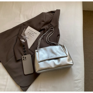 Detail of silver metallic crinkled shoulder bag with sleek chain strap and flap closure
