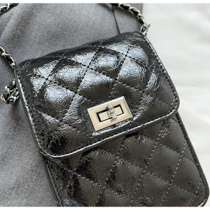 Close-up of black quilted leather texture and silver metallic twist lock closure