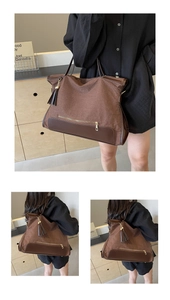 Detail view of large brown canvas tote bag with woven texture and gold zipper tassel