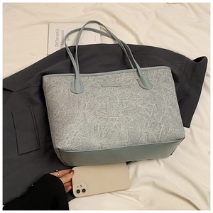 Large blue tote bag with textured fabric and leather base shown with phone for size reference