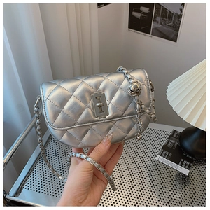 Detailed view of silver quilted crossbody bag with metal chain strap and twist lock