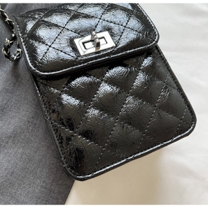 Detail view of glossy black quilted leather mini bag with silver clasp and chain