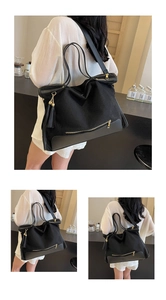 Macro shot of black canvas and leather tote with metallic zipper and tassel detail