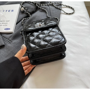 Close-up of black quilted chain bag with silver twist-lock and multi-layer interior