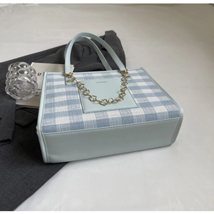 Detail of blue and white checkered tote bag with gold flower chain and brand logo