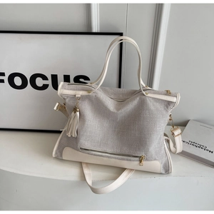 Detail of grey woven canvas tote with beige faux leather trim and decorative tassel