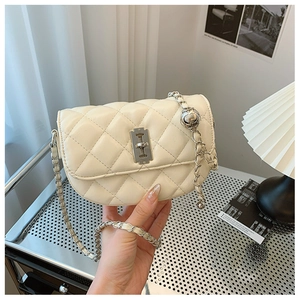 Detail of off-white quilted saddle bag with unique silver razor blade lock and chain strap