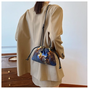 Artistic abstract print bucket bag with drawstring closure worn with a khaki suit