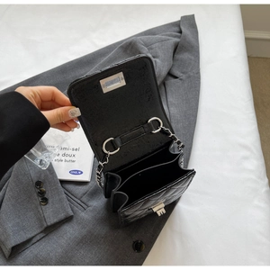 Detail of black quilted chain bag featuring dual inner compartments and silver hardware