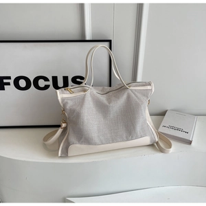 Detailed close-up of a large canvas tote bag showing grey fabric texture and leather trim