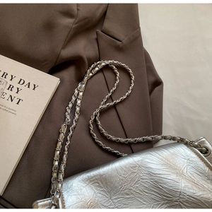 Macro shot of silver crinkled leather texture and metallic chain strap on shoulder bag