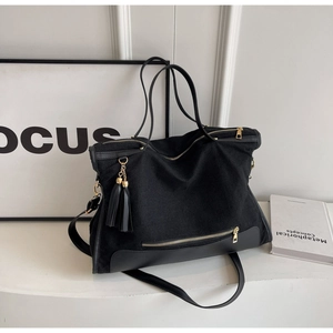 Detail of black canvas tote bag with gold zipper pocket and stylish double tassel accents