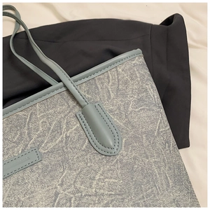 Detail of blue textured tote bag showing high-quality stitching and light blue leather strap