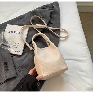 Vue détaillée du sac seau en cuir crème sur blazer gris avec bandoulière réglable