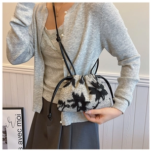 Detail of vintage oil painting style bucket bag with knit texture and leather strap
