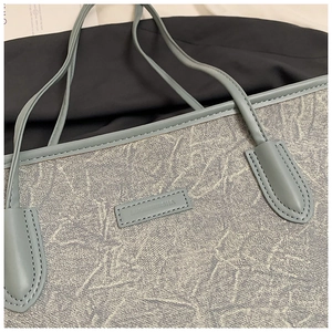 Detail of marble texture tote bag with blue reinforced leather straps and stitched label