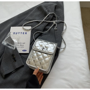 Detail of silver quilted texture and metal chain strap on a compact crossbody bag