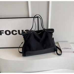 Detailed close-up of a large black tote bag with dual leather handles and secure zip closure