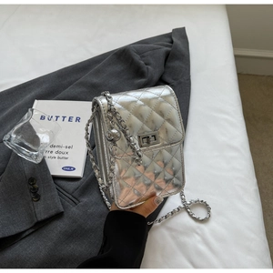 Detailed view of silver quilted crossbody bag with metal chain and turn-lock closure