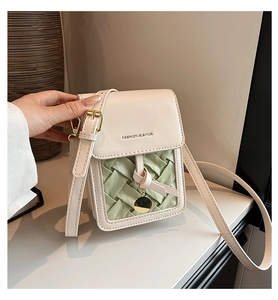 Detail of crossbody phone bag with mint green weave and gold charm decoration