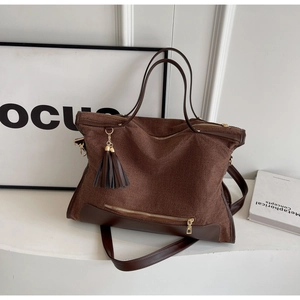 Detail of woven canvas tote with dark brown leather trim and golden zipper tassel