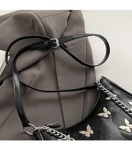 Detail of pleated black leather bag with silver butterfly charm and chain strap