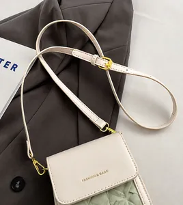 Detail of white faux leather crossbody bag with adjustable strap and golden buckle