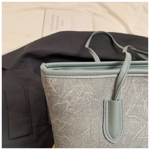Macro shot of light blue textured leather tote bag showing detailed stitching and edge craftsmanship