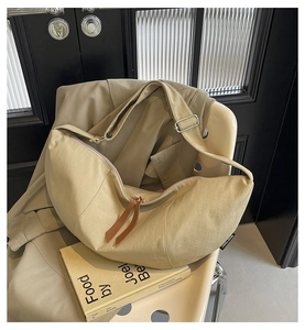 Detail of khaki crescent crossbody bag with zipper and adjustable strap on a chair