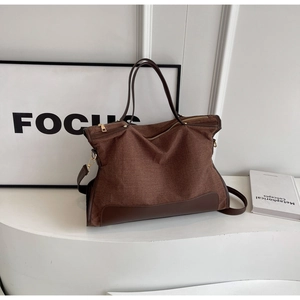 Detail of canvas tote bag with brown leather base, top handles and gold zipper closure